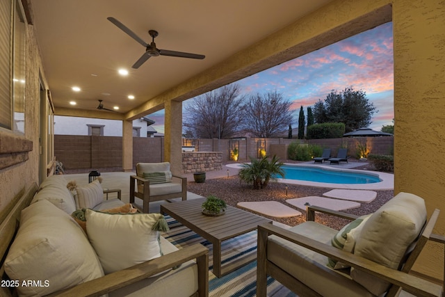 patio terrace at dusk with ceiling fan, an outdoor hangout area, and a fenced in pool