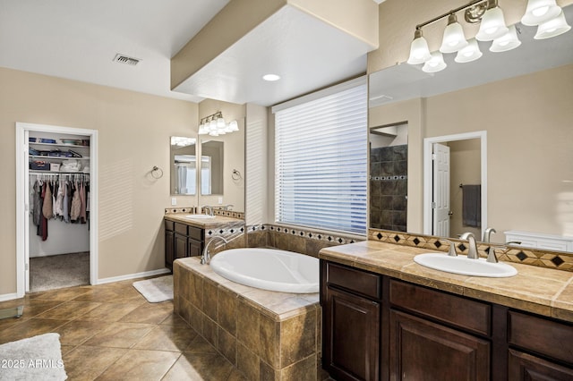 bathroom with vanity, tile patterned floors, and a relaxing tiled tub