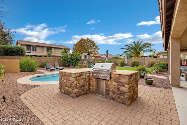 view of patio / terrace featuring an outdoor kitchen, a fenced in pool, grilling area, and a playground