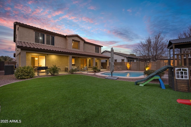 back house at dusk featuring a fenced in pool, central AC, a lawn, and a patio