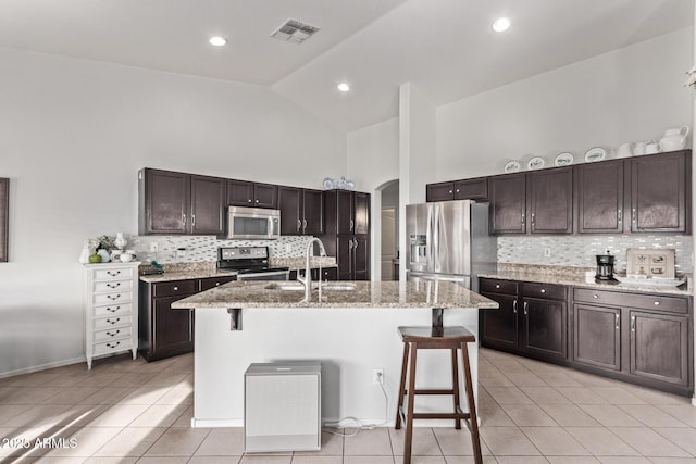 kitchen with sink, stainless steel appliances, a kitchen breakfast bar, and a center island with sink