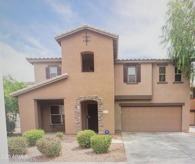 mediterranean / spanish-style house featuring concrete driveway, an attached garage, a tiled roof, and stucco siding