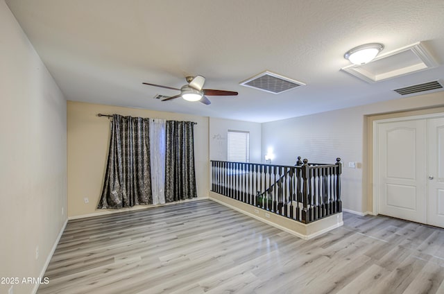 empty room featuring wood finished floors, visible vents, and a ceiling fan