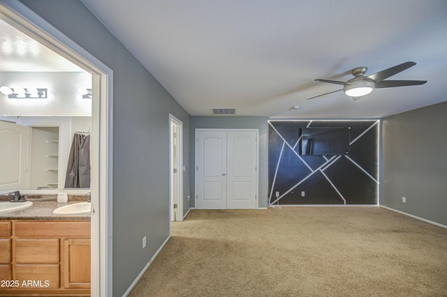 interior space featuring baseboards, carpet flooring, a sink, and visible vents