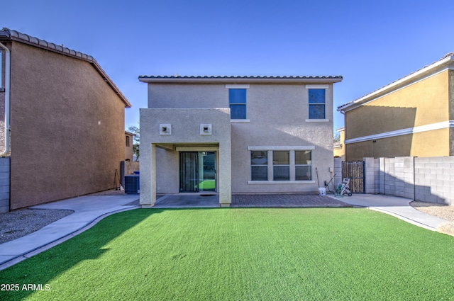 back of property with stucco siding, fence, a patio, and a lawn