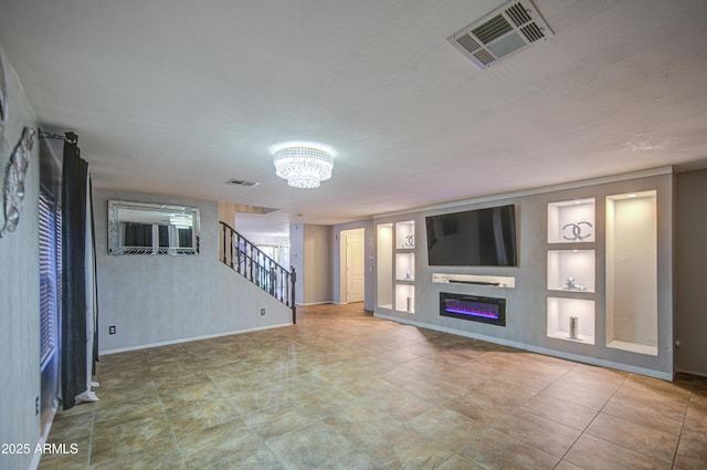 unfurnished living room featuring baseboards, a notable chandelier, built in features, and visible vents