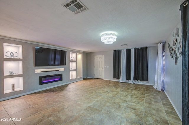 unfurnished living room with baseboards, a glass covered fireplace, visible vents, and an inviting chandelier