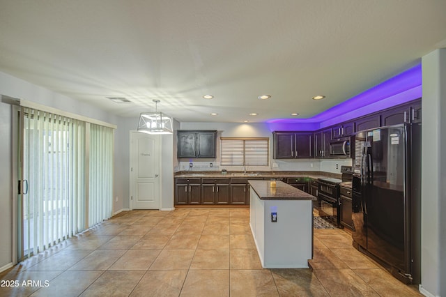kitchen featuring dark stone counters, black appliances, light tile patterned flooring, and a kitchen island