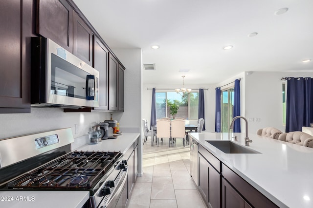 kitchen with appliances with stainless steel finishes, sink, a notable chandelier, hanging light fixtures, and light tile patterned flooring