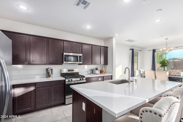 kitchen featuring pendant lighting, an inviting chandelier, sink, an island with sink, and stainless steel appliances