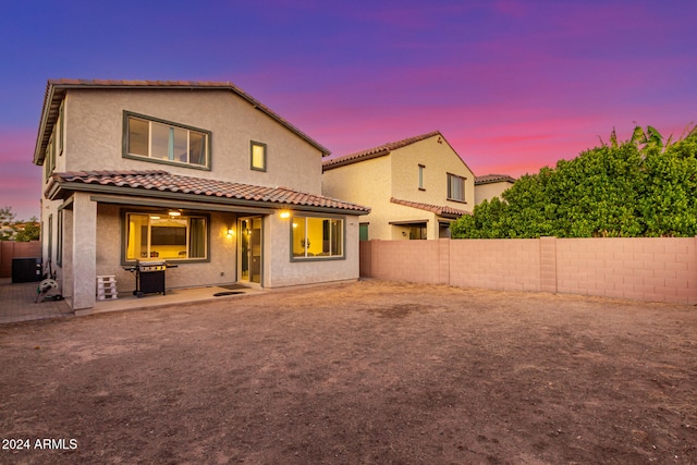 back house at dusk with a patio area