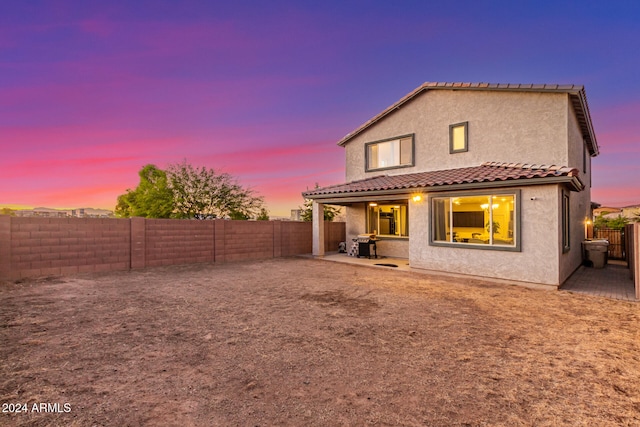 back house at dusk with a patio area