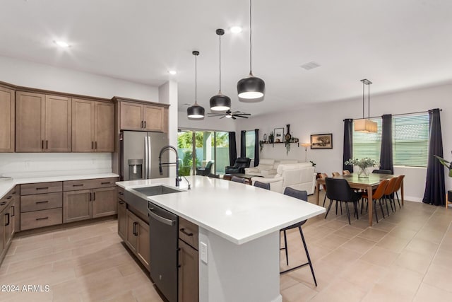 kitchen featuring a center island with sink, stainless steel appliances, a kitchen breakfast bar, pendant lighting, and sink