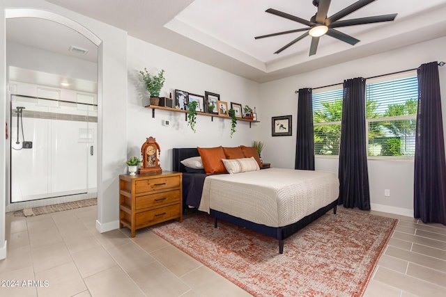 bedroom with ceiling fan, light tile patterned floors, and a tray ceiling