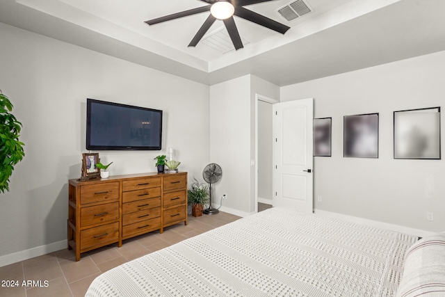 bedroom featuring ceiling fan, a tray ceiling, and light tile patterned floors