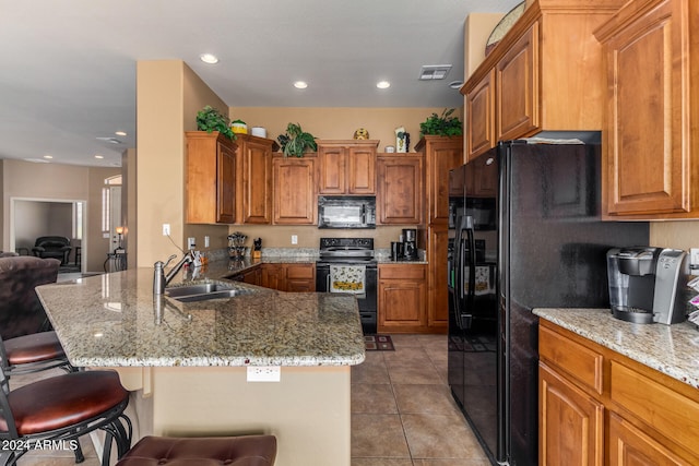 kitchen featuring black appliances, sink, kitchen peninsula, a kitchen breakfast bar, and light tile patterned floors