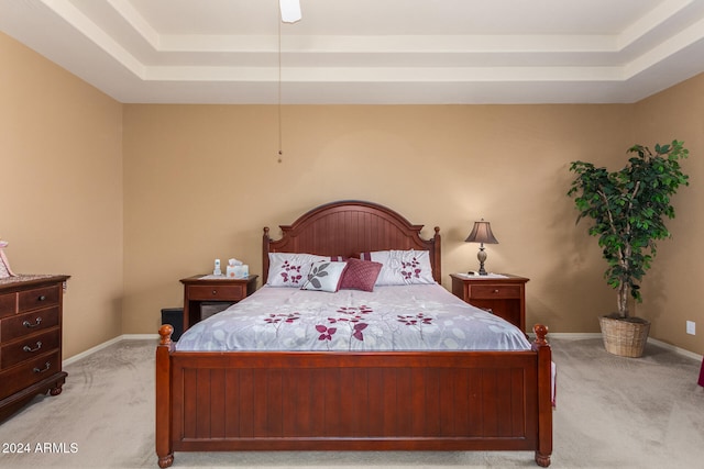 carpeted bedroom featuring a tray ceiling and ceiling fan