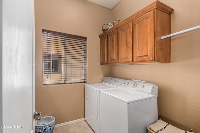 laundry area featuring light tile patterned floors, washing machine and dryer, and cabinets