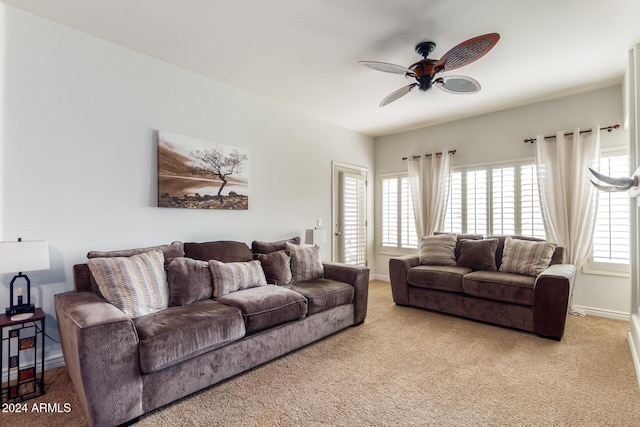 living area with a ceiling fan, light colored carpet, and baseboards