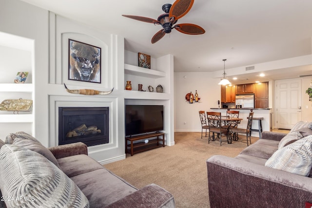 living room with light carpet, baseboards, visible vents, a glass covered fireplace, and built in shelves