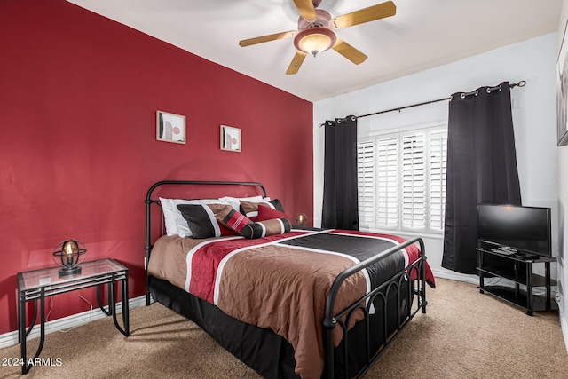 bedroom featuring light carpet, an accent wall, a ceiling fan, and baseboards