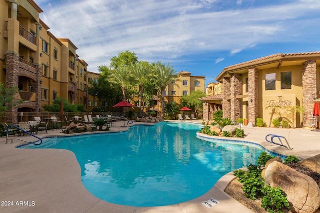 community pool with a patio area and fence