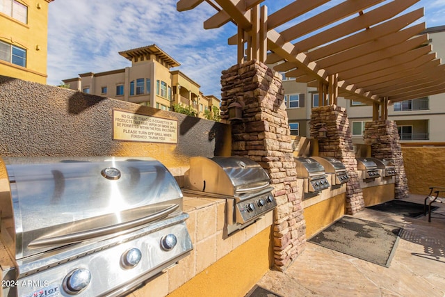 view of patio with exterior kitchen, grilling area, and a pergola