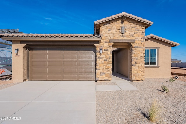 view of front of property with a tile roof, stucco siding, a garage, and concrete driveway