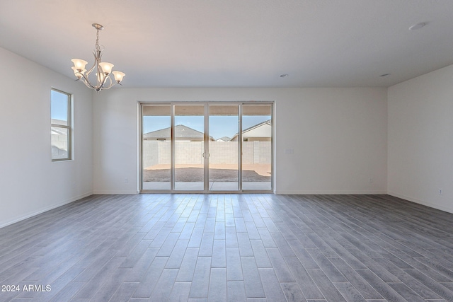 spare room with hardwood / wood-style flooring and a notable chandelier