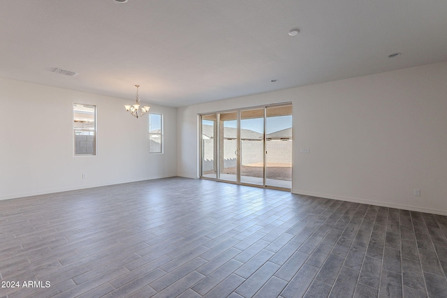 empty room featuring hardwood / wood-style flooring and a notable chandelier