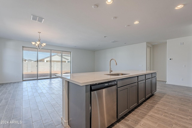 kitchen featuring sink, an inviting chandelier, light hardwood / wood-style flooring, stainless steel dishwasher, and a kitchen island with sink