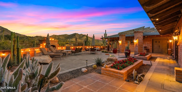 patio terrace at dusk with a warm lit fireplace and a mountain view