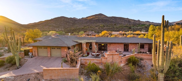 view of front of property featuring a garage, driveway, brick siding, and a mountain view