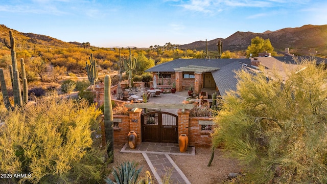 exterior space with a mountain view, a gate, fence, and a patio