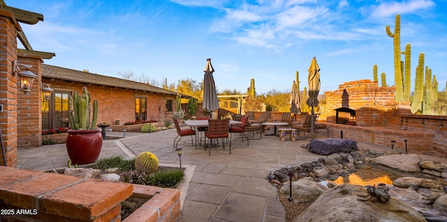 view of patio featuring an outdoor brick fireplace and outdoor dining space