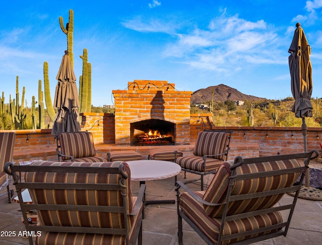 view of patio featuring an outdoor brick fireplace and a mountain view