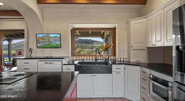 kitchen featuring arched walkways, electric cooktop, white cabinetry, stainless steel refrigerator with ice dispenser, and a sink