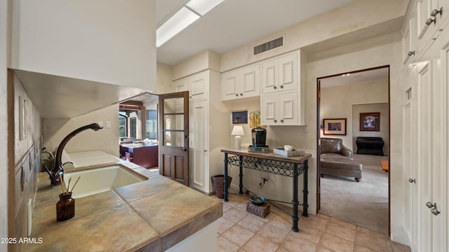 interior space featuring white cabinets, visible vents, and light carpet