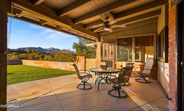 view of patio with ceiling fan, outdoor dining area, and a mountain view