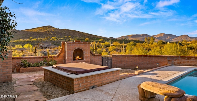 exterior space featuring an outdoor brick fireplace, a patio area, and a mountain view