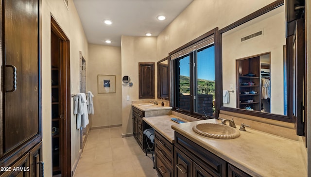 bathroom featuring visible vents, baseboards, a walk in closet, vanity, and recessed lighting