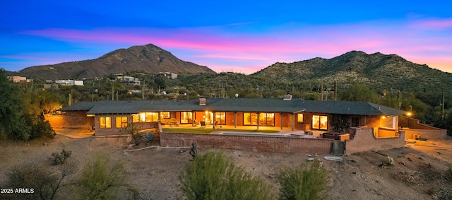 back of property at dusk with a patio and a mountain view