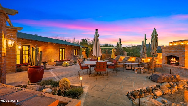 view of patio with an outdoor brick fireplace and outdoor dining area