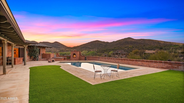 outdoor pool featuring a patio, a lawn, and a mountain view