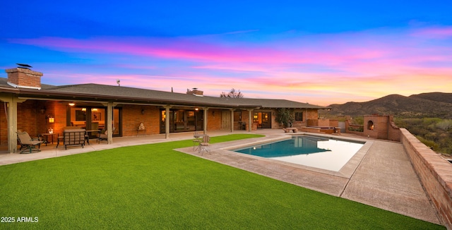 pool featuring a yard, a patio area, and a mountain view