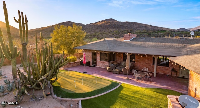 back of property featuring fence, a mountain view, a chimney, and a patio