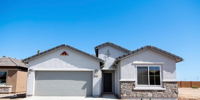 ranch-style home featuring a garage, stone siding, and stucco siding