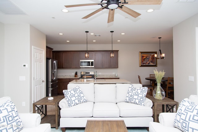 living area featuring ceiling fan with notable chandelier, visible vents, and recessed lighting