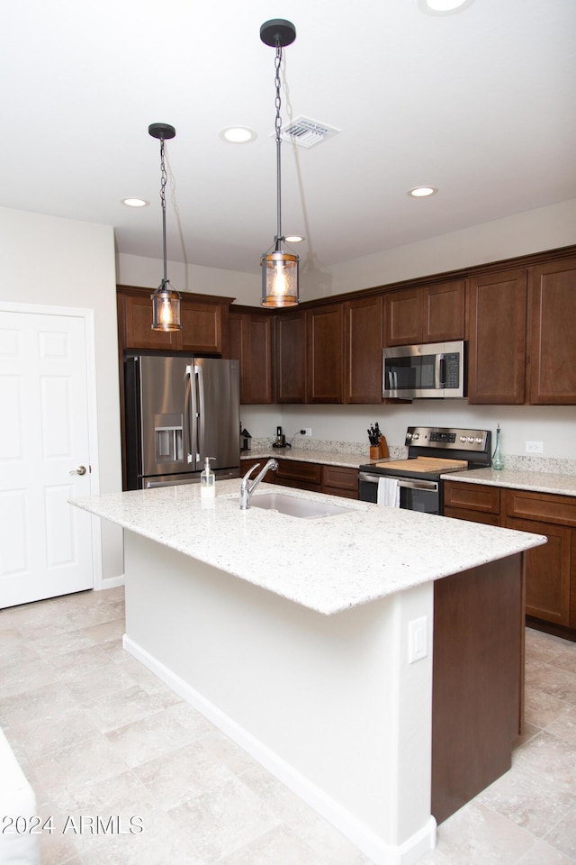 kitchen featuring pendant lighting, stainless steel appliances, visible vents, a kitchen island with sink, and a sink