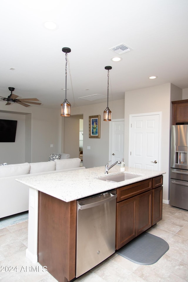 kitchen with stainless steel appliances, visible vents, open floor plan, a sink, and an island with sink